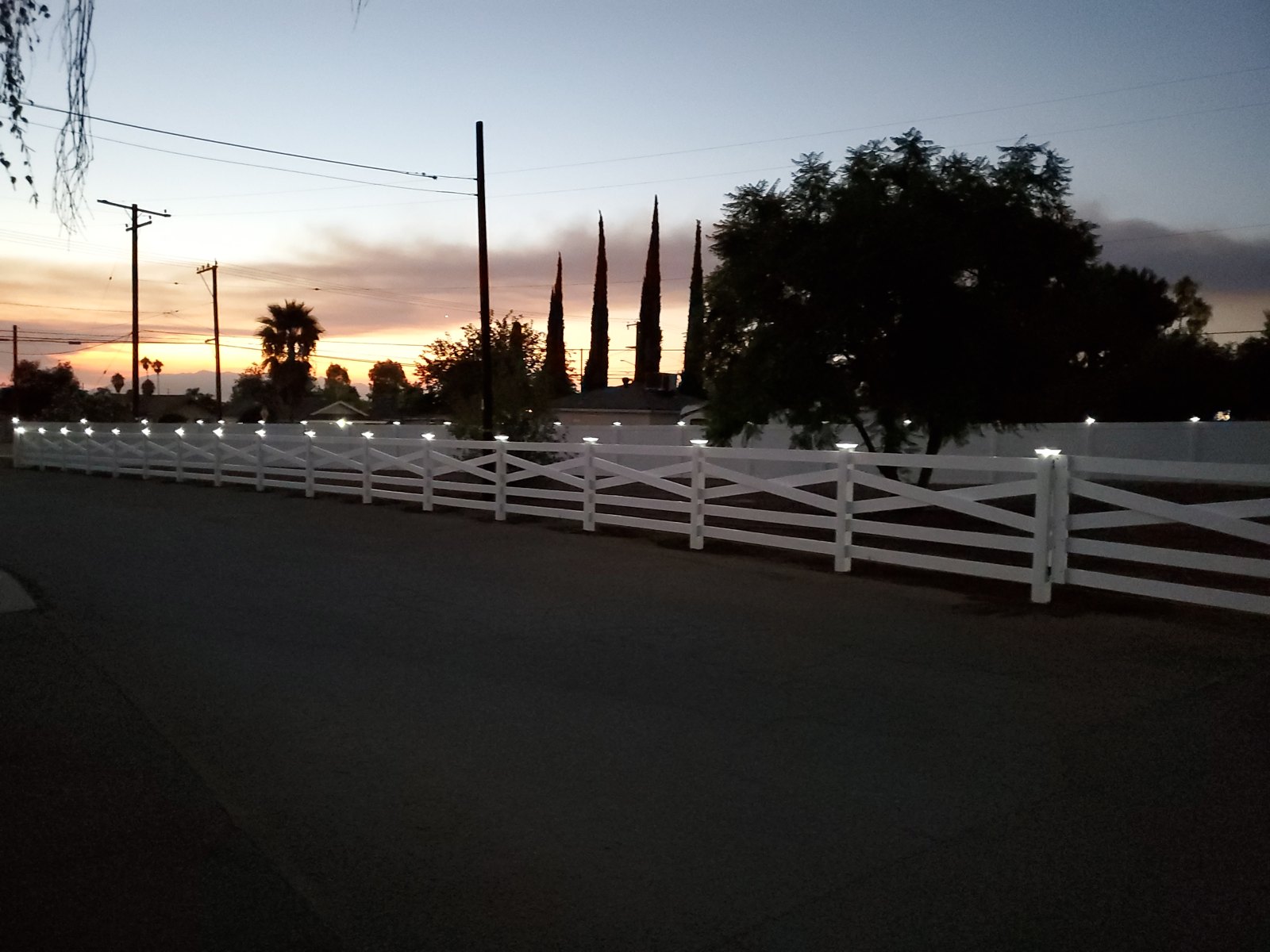 White vinyl ranch rail fence with solar post lights at sunset in Yucaipa, CA